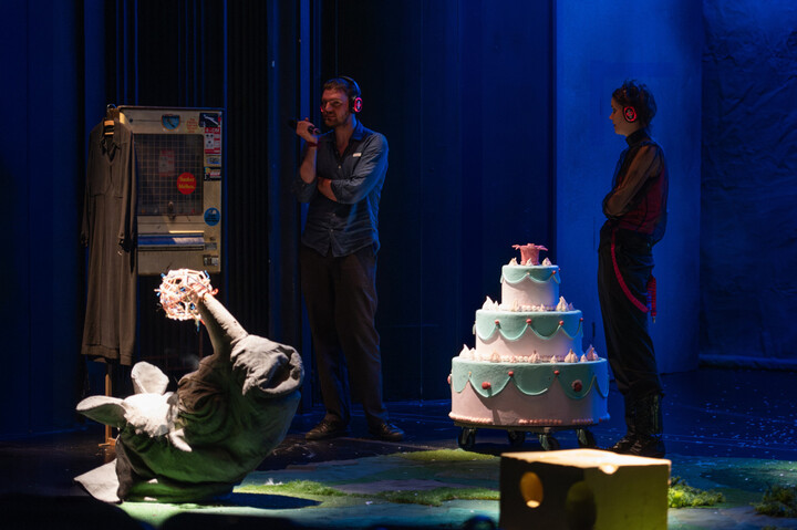 A performer and audience member speak to a cigarette machine