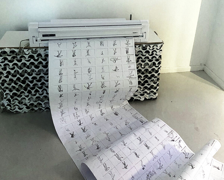 A plotter fills a long roll of paper rows of small figure-drawings contributed by the audience.