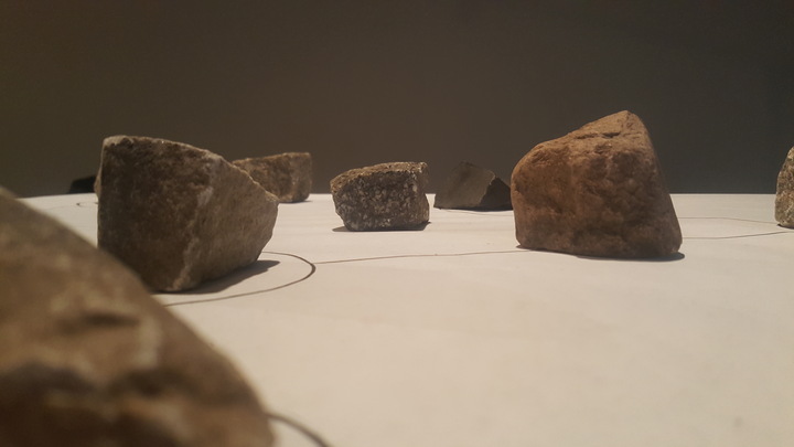 Rough stones of varying sizes arranged on a white surface marked with a thin hand-drawn network of lines.